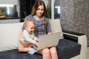 Homeoffice mit Kind: Utopie oder doch möglich? Mutter arbeitet am Laptop - Baby sitzt dabei