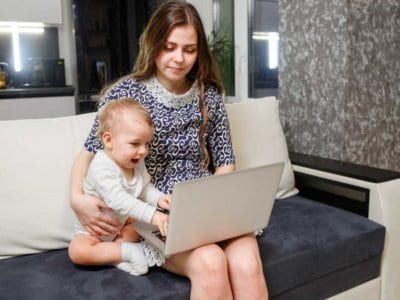 Homeoffice mit Kind: Utopie oder doch möglich? Mutter arbeitet am Laptop - Baby sitzt dabei